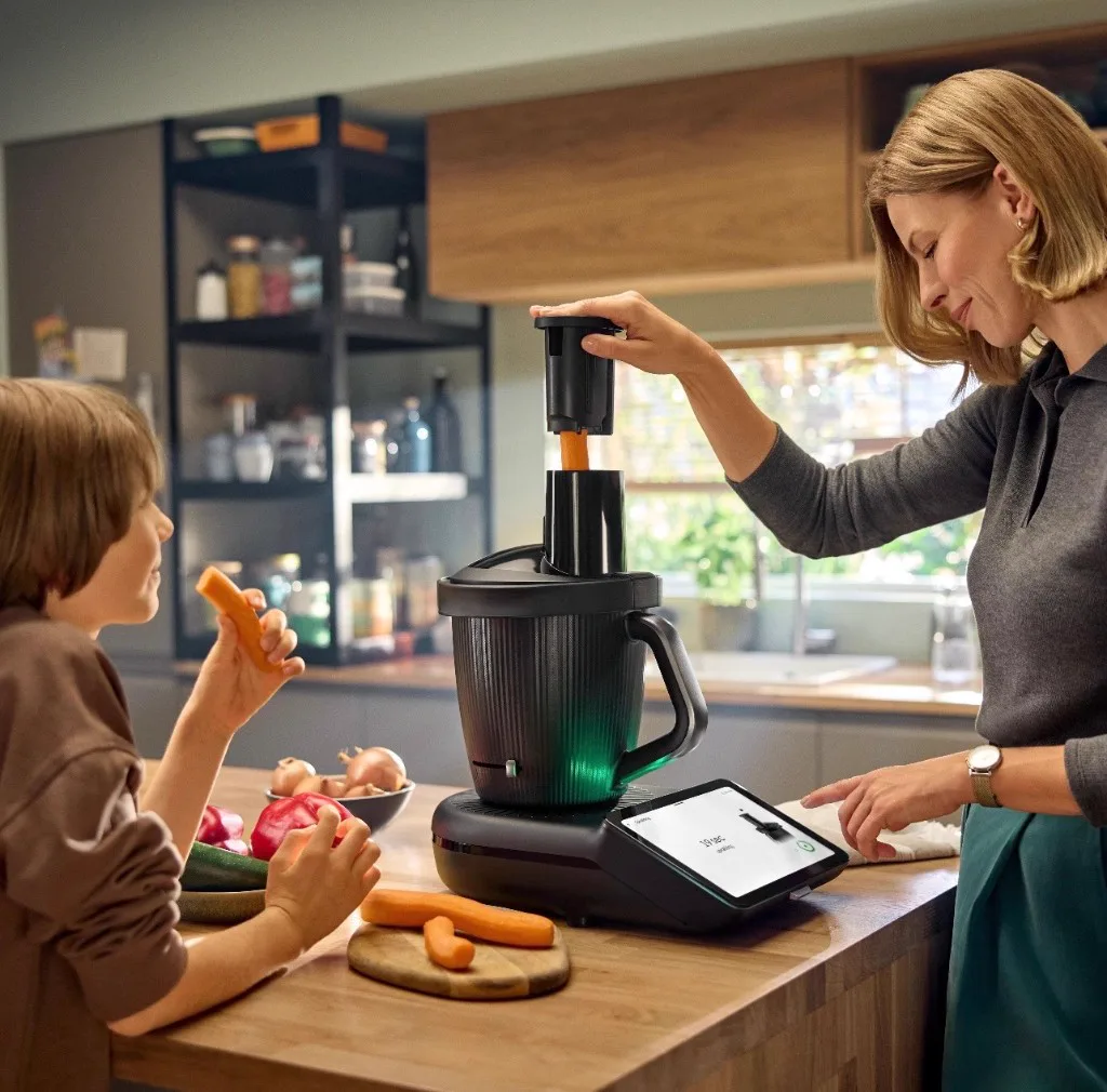 Parent and child using Thermomix to slice carrots in the kitchen