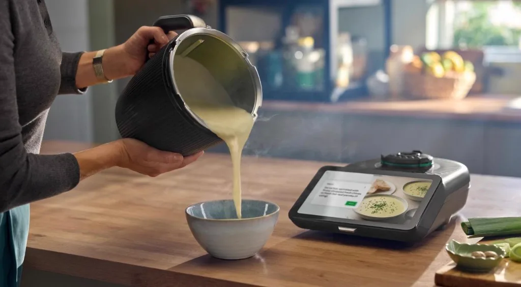 Smooth homemade soup being poured from a Thermomix bowl